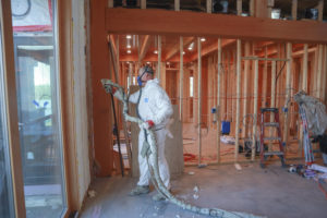Man in protective suit spraying a wall with insulating foam