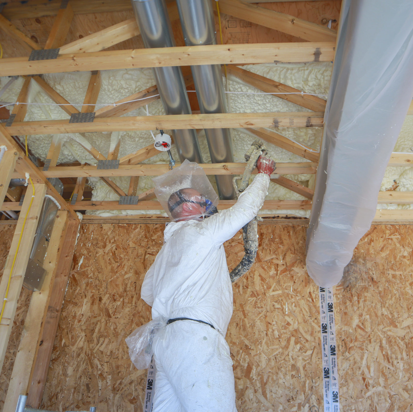 Man in protective suit spraying a ceiling with insulating foam